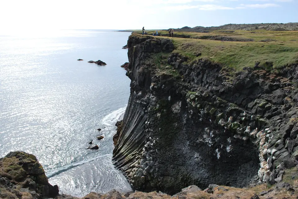 Basaltklippor vid Arnarstapi med hav och strand i motljus