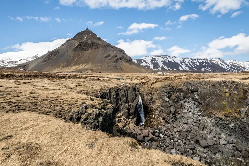 Stapafell über Basaltklippen mit kleinem Wasserfall bei Arnarstapi