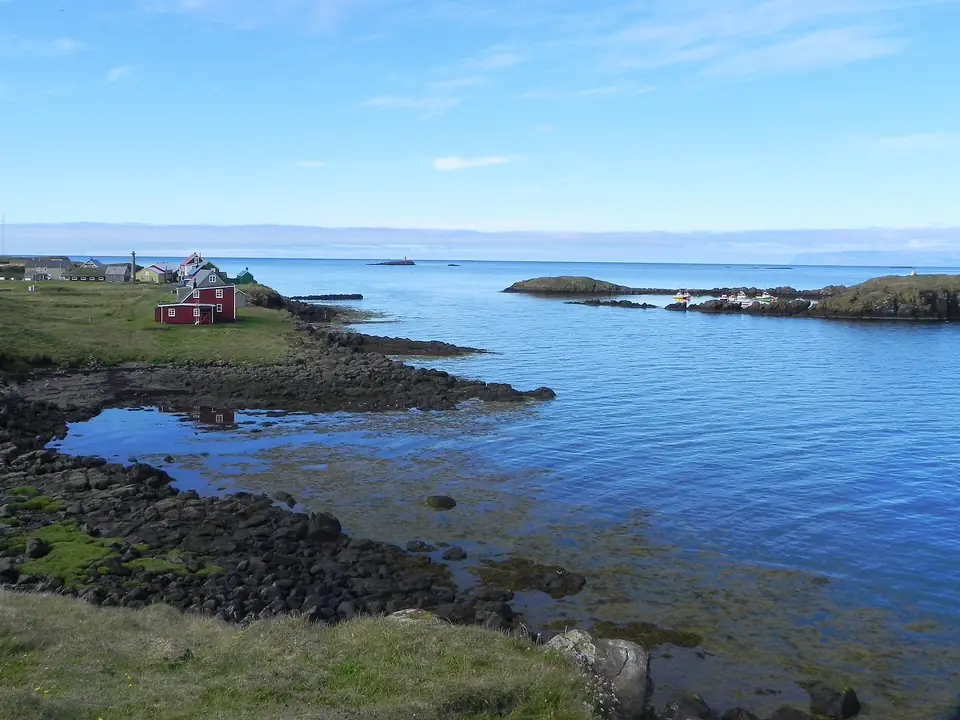 Küste der Insel Flatey mit rotem Haus und ruhigem Wasser