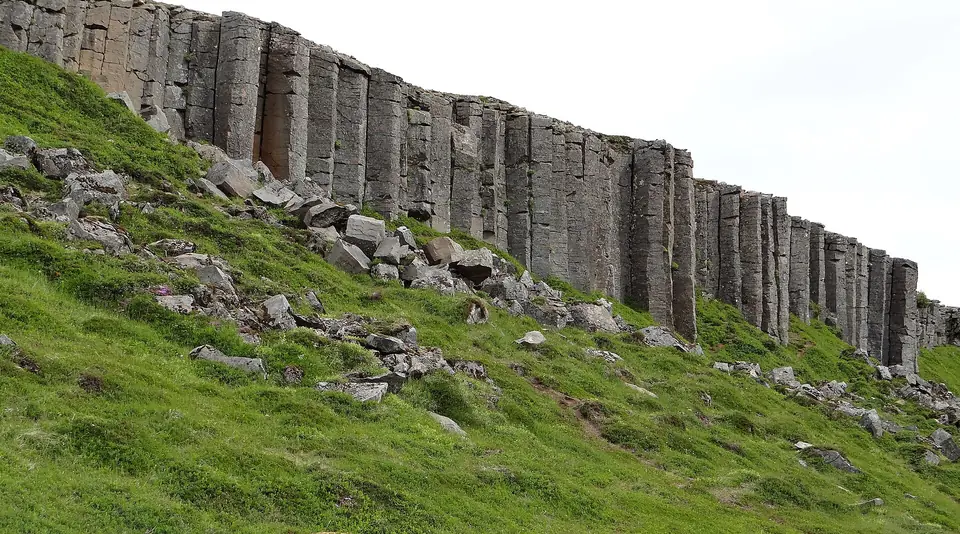 Wand aus Basaltsäulen Gerðuberg über einem grünen Hang