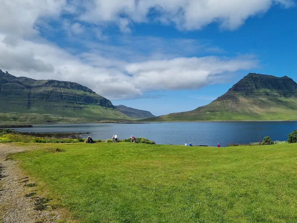 Viken vid Grundarfjörður med grön äng och berg under blå himmel