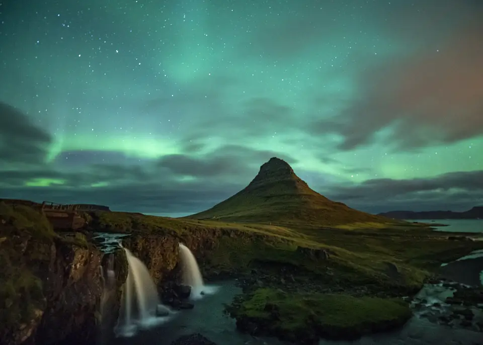 Grünes Nordlicht über dem Kirkjufell und dem Wasserfall Kirkjufellsfoss bei Nacht