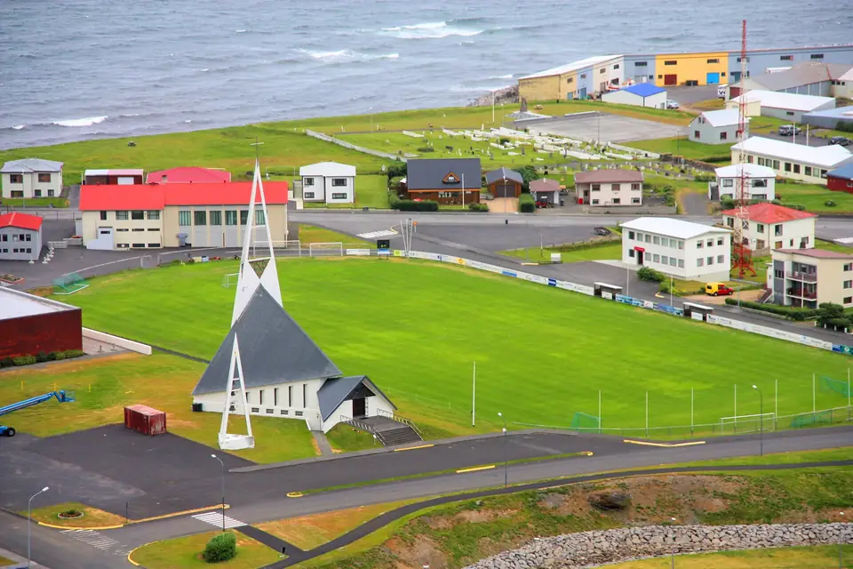 L’église moderne d’Ólafsvík et sa flèche pointue, au-dessus d’un terrain de sport, côte nord