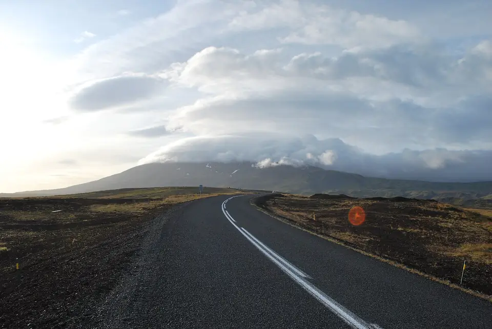 Route asphaltée près de Hellnar, avec en arrière-plan le glacier du Snæfellsjökull dans les nuages