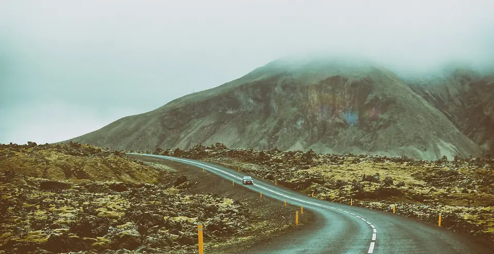 Straße durch ein moosbewachsenes Lavafeld mit Berg im Hintergrund auf Snæfellsnes