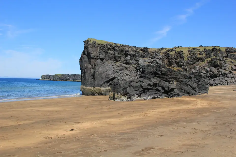 Geel zandstrand Skarðsvík met donkere lavarots