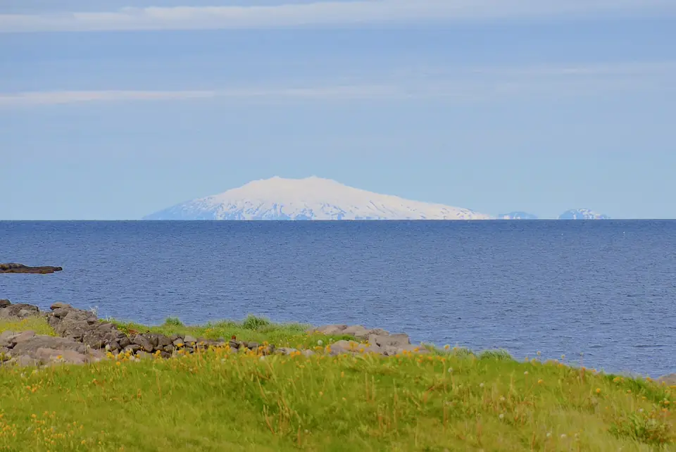Der Snæfellsjökull als weiße Kuppe über dem Meer, aus großer Entfernung gesehen