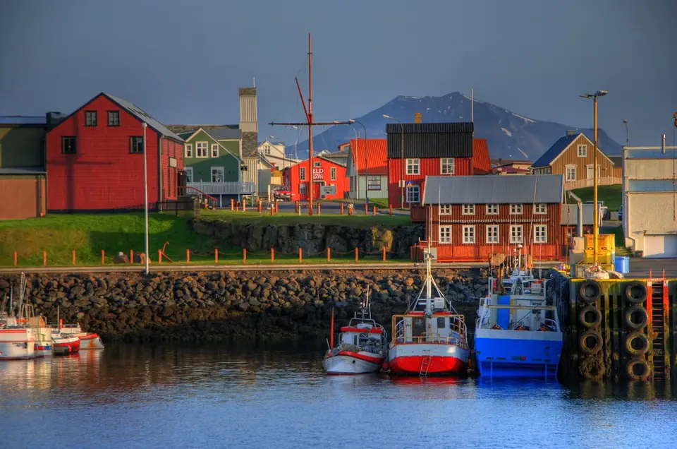 Röda och gula hus vid hamnen i Stykkishólmur med båtar
