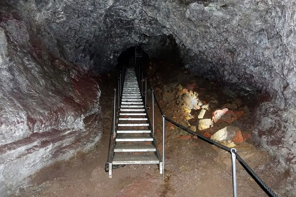 Metalltreppe in der Lavaröhre Vatnshellir mit rötlichen Höhlenwänden